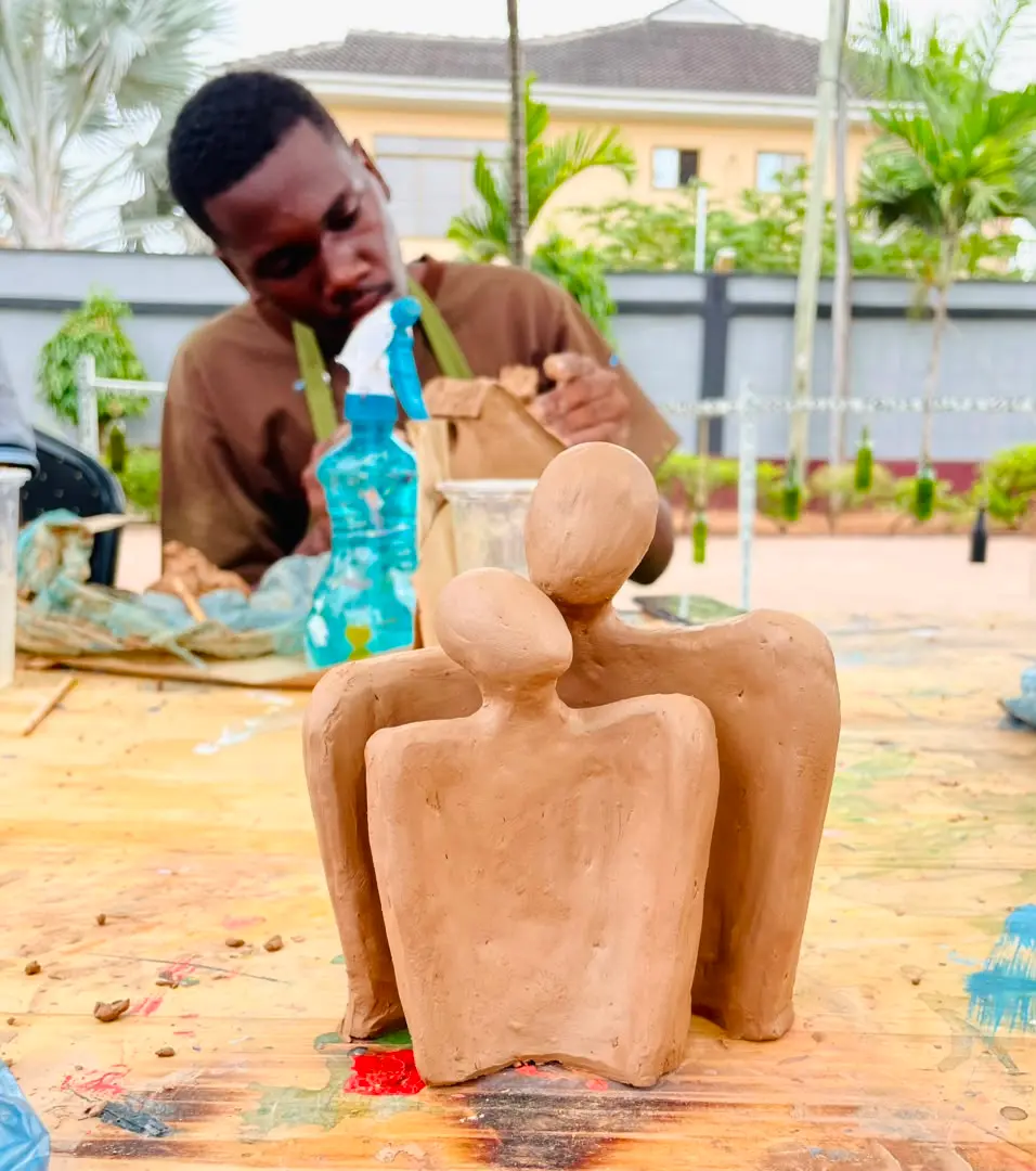 A guest shaping a clay figure by hand during a pottery session at the studio